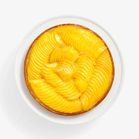 Overhead of Lady M’s Tarte à la Mangue with mango slices and a glossy glaze on a golden crust.