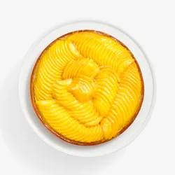 Overhead of Lady M’s Tarte à la Mangue with mango slices and a glossy glaze on a golden crust.