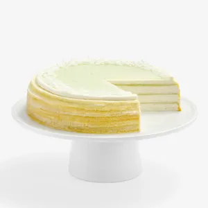 Lady M Pandan Kaya Mille Crêpes sliced, showing crêpe layers, pandan glaze, cream, and coconut flakes.