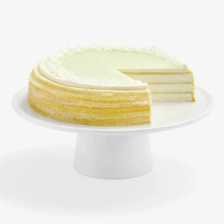 Lady M Pandan Kaya Mille Crêpes sliced, showing crêpe layers, pandan glaze, cream, and coconut flakes.