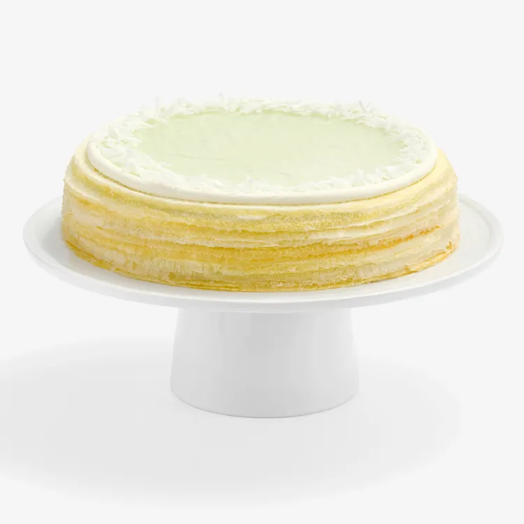 Whole Lady M Pandan Kaya Mille Crêpes with golden layers, green glaze, cream, and coconut flakes.