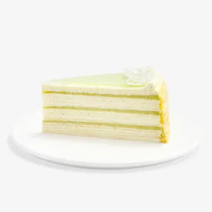Slice of Lady M Pandan Kaya Mille Crêpes with cream, pandan custard, green glaze, and coconut.