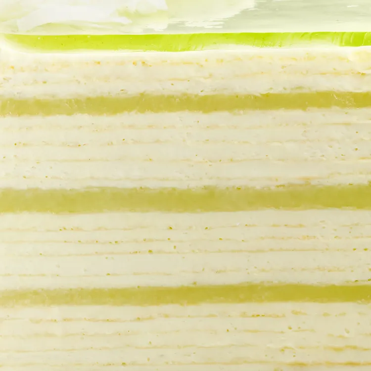 Close-up of Lady M Pandan Kaya Mille Crêpes with layers of crêpes, cream, and green custard.