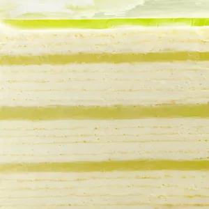 Close-up of Lady M Pandan Kaya Mille Crêpes with layers of crêpes, cream, and green custard.