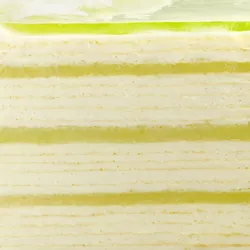 Close-up of Lady M Pandan Kaya Mille Crêpes with layers of crêpes, cream, and green custard.