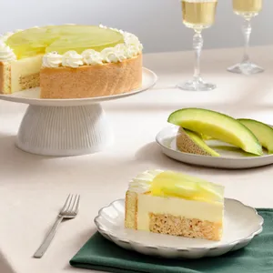 Melon cake on stand, slice on plate with melon, and two champagne glasses.
