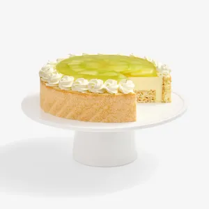 A Lady M Charlotte au Melon cake with one slice removed, on a white cake stand.