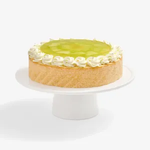 Whole Lady M Charlotte au Melon cake with cream rosettes and melon jelly on a white stand.