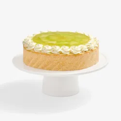 Whole Lady M Charlotte au Melon cake with cream rosettes and melon jelly on a white stand.