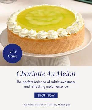 Lady M's Charlotte Au Melon cake, featuring a vibrant green melon terrine topping and delicate whipped cream rosettes.