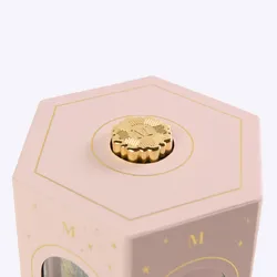 A close-up of the decorative gold 'M' knob on top of the pink lantern gift set.