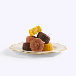 A stack of colorful pink, yellow, and brown mooncakes on a white and gold scalloped plate.