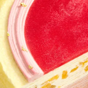 A close-up on top of Peach Melba cake, showing red jelly, piped pink cream, and gold flakes.