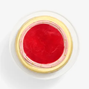 An overhead view of Peach Melba Mille Crêpes with a red jelly top and pink, gold-flecked cream.