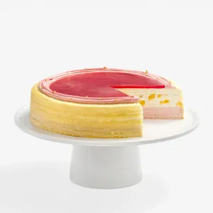 A Peach Melba Mille Crêpes cake on a white stand with one slice cut out to show the layers.
