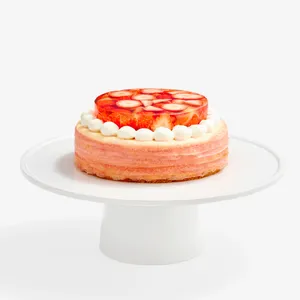 An Oishii Berry Trois Mille Crêpes cake with a strawberry gelée top, set on a white cake stand.