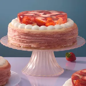 An Oishii Berry Trois Mille Crêpes on a pink glass stand with a fresh strawberry sitting nearby.