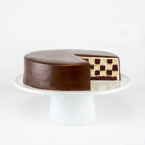 A Lady M Checker's cake sliced into on a white cake stand.