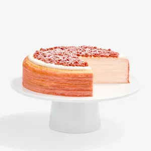 A sliced into Lady M Pink Pearl Mille Crêpes set on top a white cake stand.