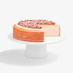 A sliced into Lady M Pink Pearl Mille Crêpes set on top a white cake stand.
