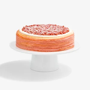 A Lady M Pink Pearl Mille Crêpes set on top a white cake stand.