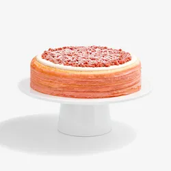 A Lady M Pink Pearl Mille Crêpes set on top a white cake stand.