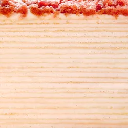 A Lady M Pink Pearl Mille Crêpes detail shot. Crêpe layers, cream, and strawberry streusel & pearls.