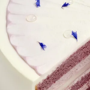 Close-up of a Lady M Taro Mochi Cream Cake. Layers of sponge cake, mochi, cream, & edible petals.