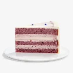 A Lady M Taro Mochi Cream Cake slice set on top a white round cake plate.