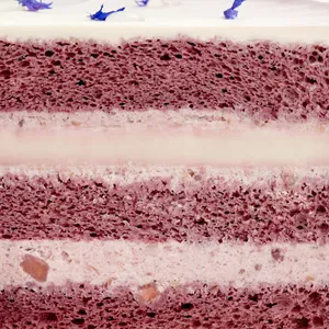 A Lady M Taro Mochi Cream Cake detail shot. Layers of sponge cake, mochi, cream, & edible petals.