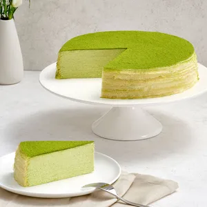 A Lady M Gluten-Free Green Tea Mille Crêpes with one slice on a plate. Set on top a marble table.