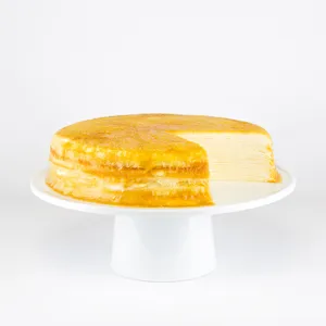 A sliced into Lady M Gluten-Free Signature Mille Crêpes on top a white cake stand.