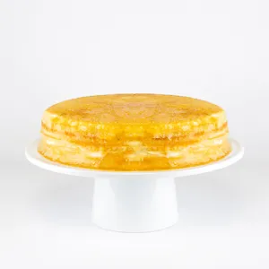 A Lady M Gluten-Free Signature Mille Crêpes on top a white cake stand.