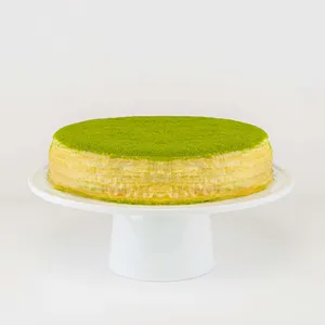 A Lady M Gluten-Free Green Tea Mille Crêpes on top a white cake stand.