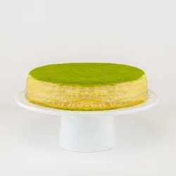 A Lady M Gluten-Free Green Tea Mille Crêpes on top a white cake stand.