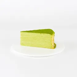 A Lady M Gluten-Free Green Tea Mille Crêpes slice on top a white round plate.