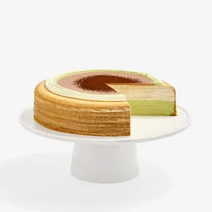 A sliced into Lady M Coffee Matcha Mille Crêpes on top a white cake stand.