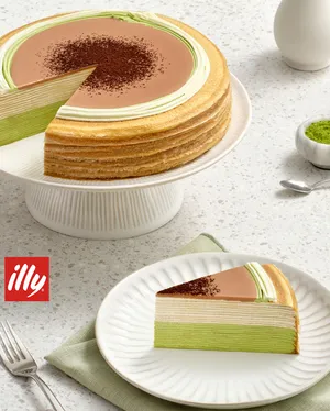 A Lady M Coffee Matcha Mille Crêpes with one slice on a plate set on a marble table.