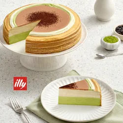A Lady M Coffee Matcha Mille Crêpes with one slice on a plate set on a marble table.
