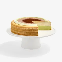 A sliced into Lady M Coffee Matcha Mille Crêpes on top a white cake stand.