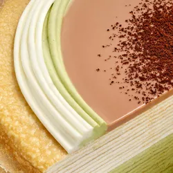 Close-up of a Lady M Coffee Matcha Mille Crêpes. Layers of crêpe, cream, glaze and coffee powder.