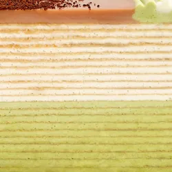 A Lady M Coffee Matcha Mille Crêpes detail shot. Layers of crêpe, cream, glaze, and coffee powder.