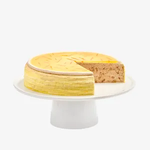 A sliced into Lady M Carrot Cake Mille Crêpes on top a white cake stand.