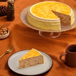 A Lady M Carrot Cake Mille Crêpes with one slice on a plate set on top an orange linen.