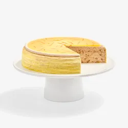 A sliced into Lady M Carrot Cake Mille Crêpes on top a white cake stand.