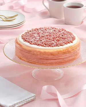 Lady M's Pink Pearl Mille Crêpes with a pink background and a ribbon