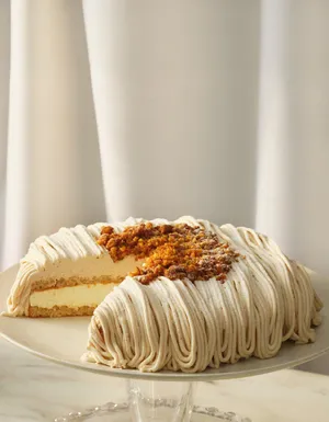 Lady M's Gateau aux Marrons cake on a glass cake stand with a slice removed.