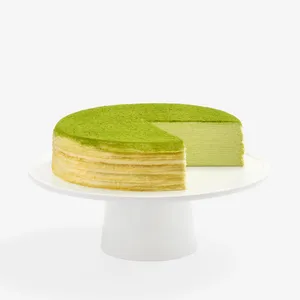 A sliced into Lady M Gluten-Free Green Tea Mille Crêpes on top a white cake stand.