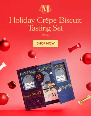 Lady M's Holiday Crêpe Biscuit Tasting Set on a red surface with ornaments and biscuits suspended.