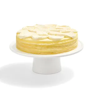 A whole Lady M Orange Mille Crepes cake on a white cake stand.